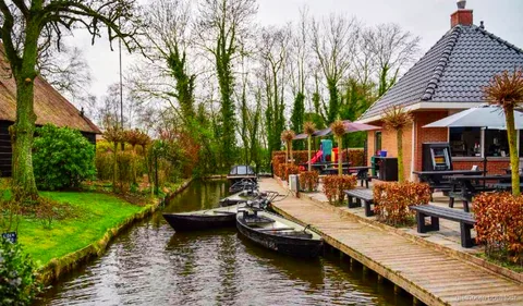 Houten boogbrug over een gracht in het dorp Giethoorn