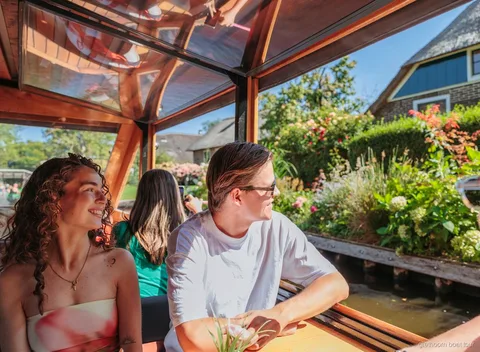 Barco de crucero pasando junto a casas con techo de paja en Giethoorn