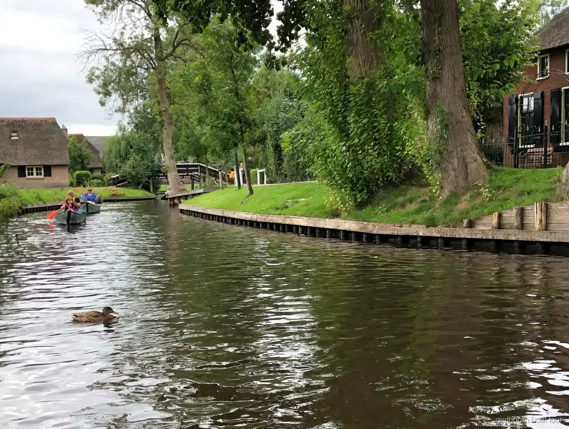 Bateau sans permis passant sous un pont en bois en arc à Giethoorn