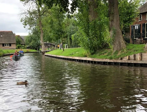Giethoorn'da ahşap kemerli bir köprünün yanından geçen kendin kullan tekne