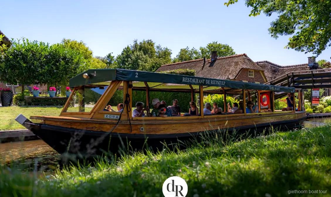 Covered cruise boat on a Giethoorn canal tour heading toward Weerribben-Wieden National Park