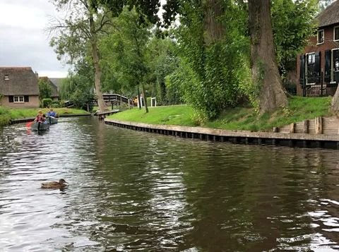 Self-drive boat passing a wooden arch bridge in Giethoorn